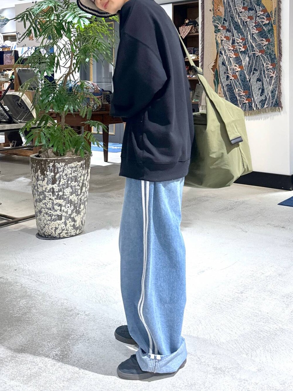 グリーン系のショルダーバッグ、ブラック系のスウェット、ホワイト系のハットを着用したメンズの冬コーディネートの4枚目の写真