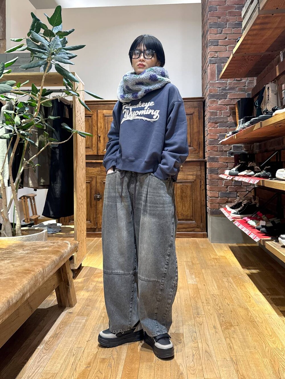 ブラウン系のデニムパンツ、ブラック系のスニーカー、ブラック系のショルダーバッグを着用したレディースの冬コーディネートの2枚目の写真