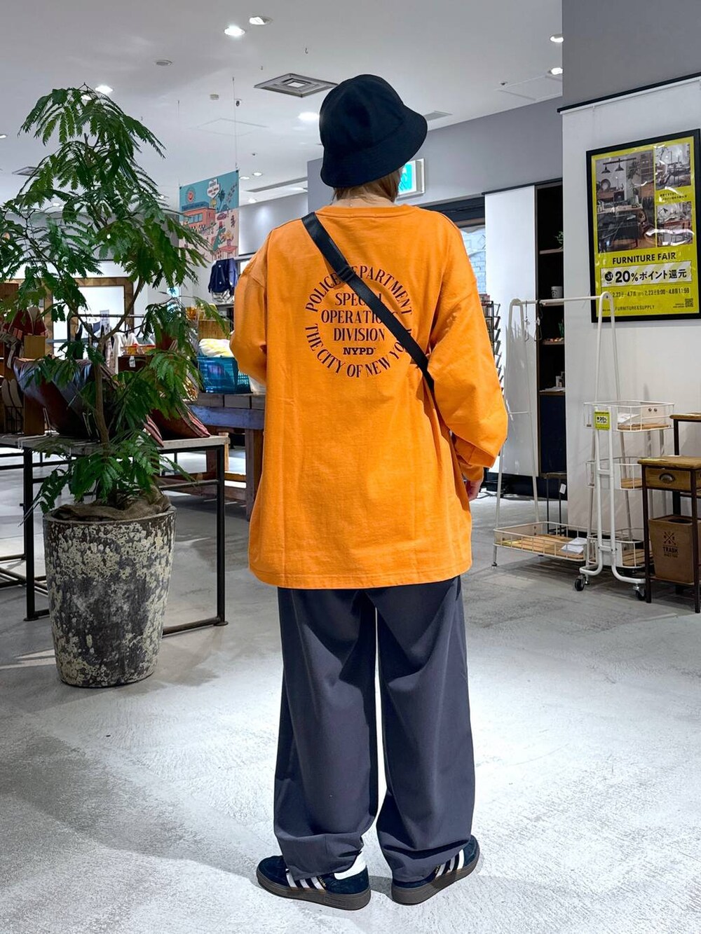 オレンジ系のTシャツ/カットソー、ブラック系のショルダーバッグ、ブラック系のスラックスを着用したメンズの冬コーディネートの4枚目の写真