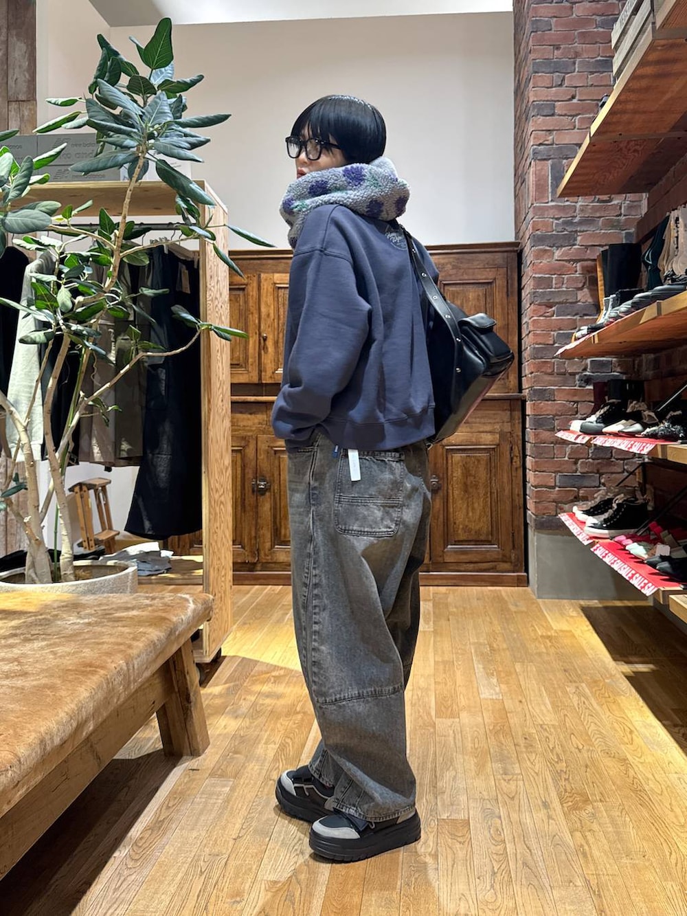 ブラウン系のデニムパンツ、ブラック系のスニーカー、ブラック系のショルダーバッグを着用したレディースの冬コーディネートの3枚目の写真