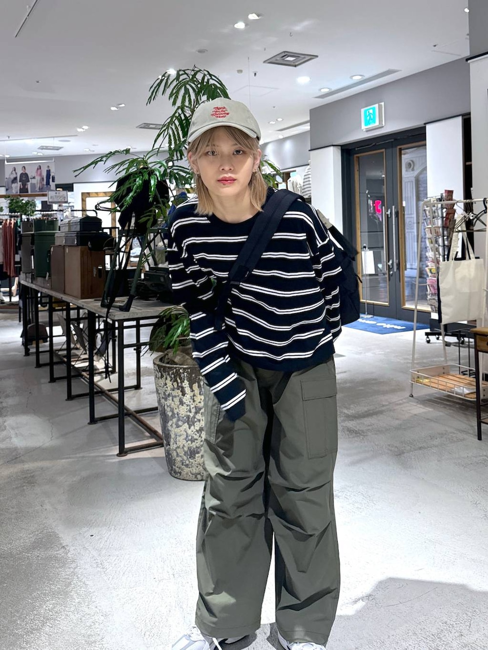 グリーン系のカーゴパンツ、ブラック系のTシャツ/カットソー、グレー系のスニーカーを着用したメンズの春コーディネートの2枚目の写真