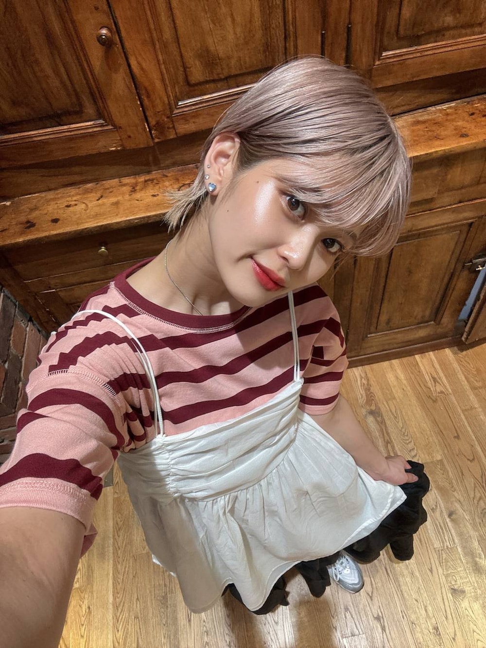 グレー系のスニーカー、ブラック系のスカート、ホワイト系のキャミソールを着用したレディースの夏コーディネートの3枚目の写真