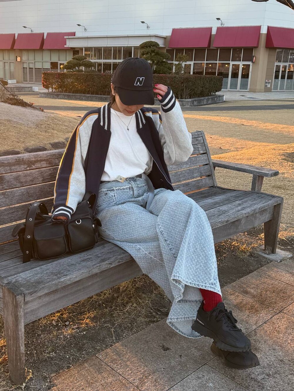 ホワイト系のTシャツ/カットソー、ブラック系のショルダーバッグ、ブルー系のデニムパンツを着用したレディースの冬コーディネートの2枚目の写真