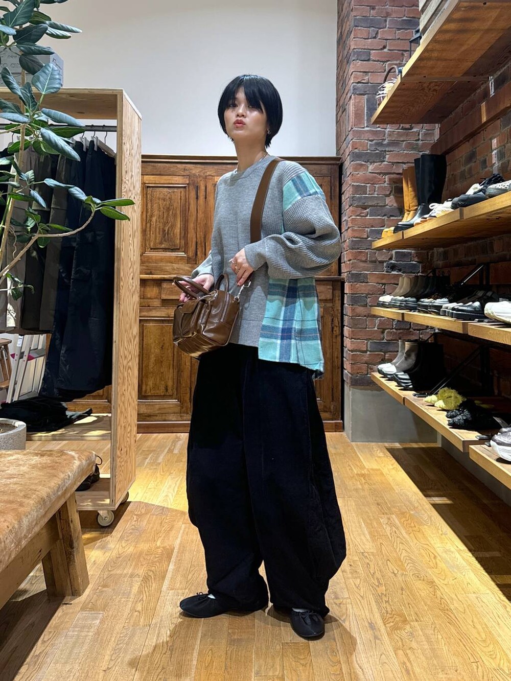 グレー系のスウェット、ブラック系のパンプス、ブラウン系のショルダーバッグを着用したレディースの秋コーディネートの2枚目の写真