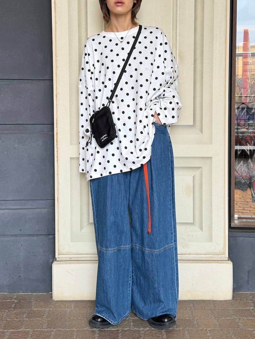 ブラック系のショルダーバッグ、ブルー系のデニムパンツ、ホワイト系のTシャツ/カットソーを着用したレディースの冬コーディネートの2枚目の写真