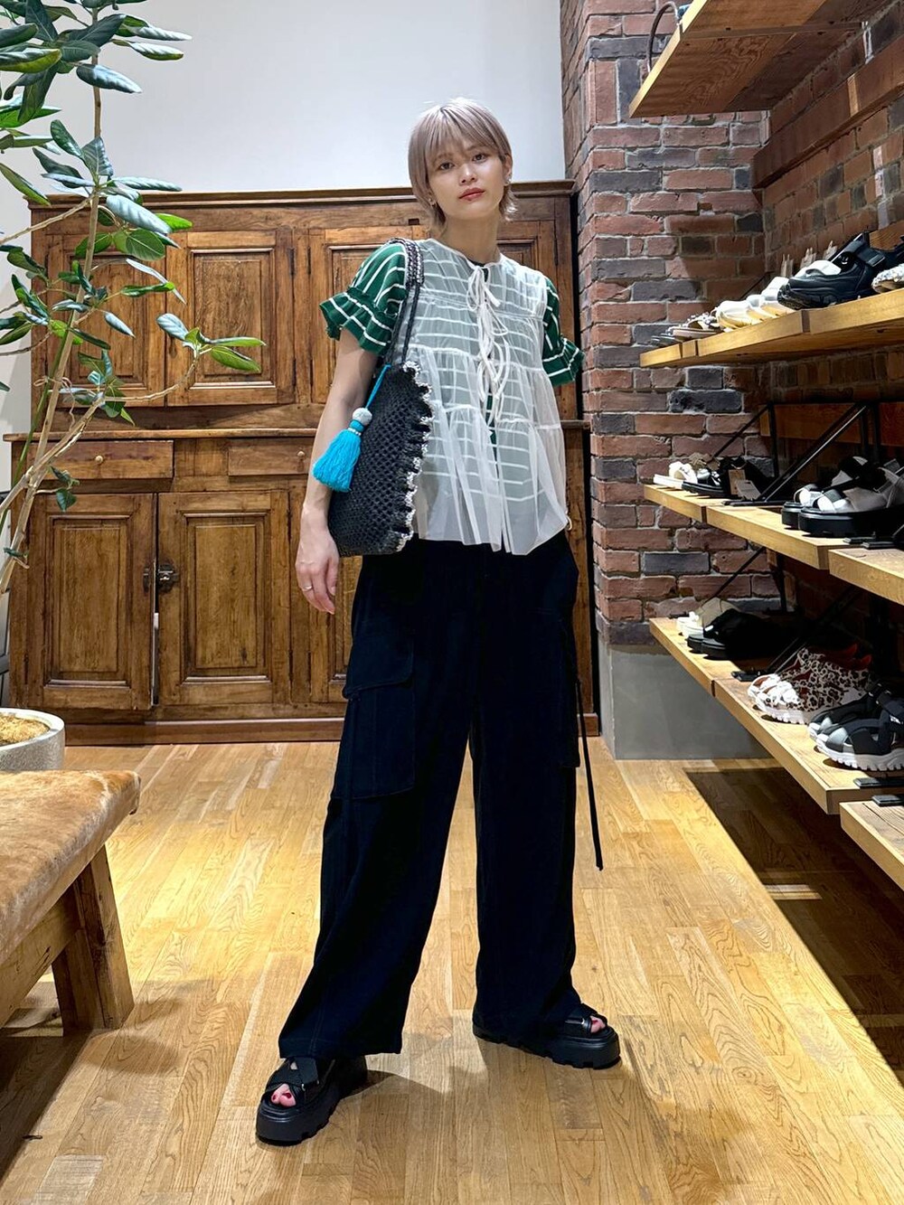 ブラック系のサンダル、ブラック系のカーゴパンツ、ホワイト系のベストを着用したレディースの夏コーディネートの2枚目の写真