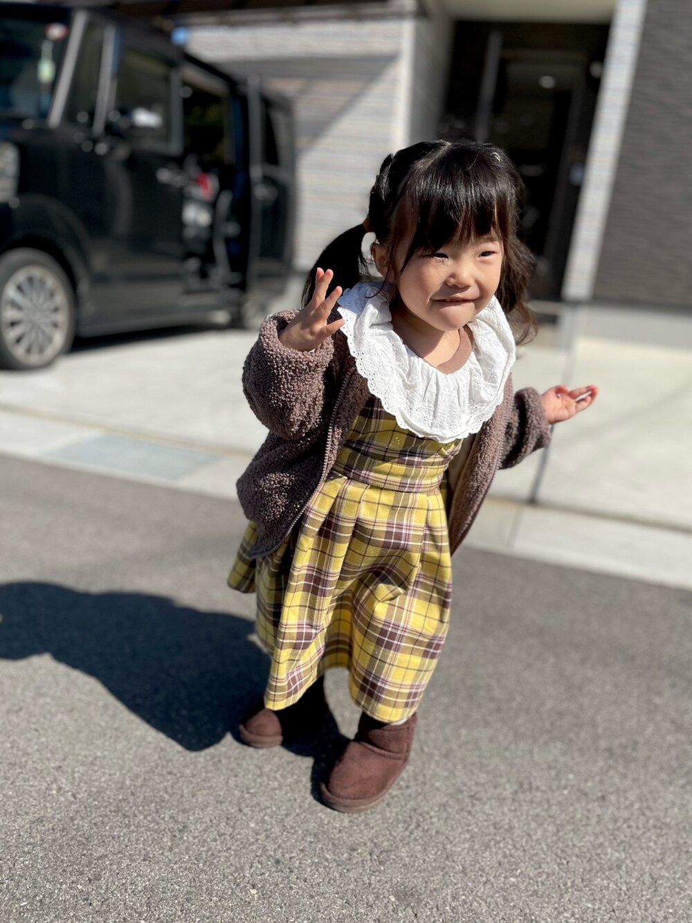 イエロー系のジャンパースカート、ブラウン系のTシャツ/カットソー、ブラウン系のブーツを着用したキッズの春コーディネートの2枚目の写真