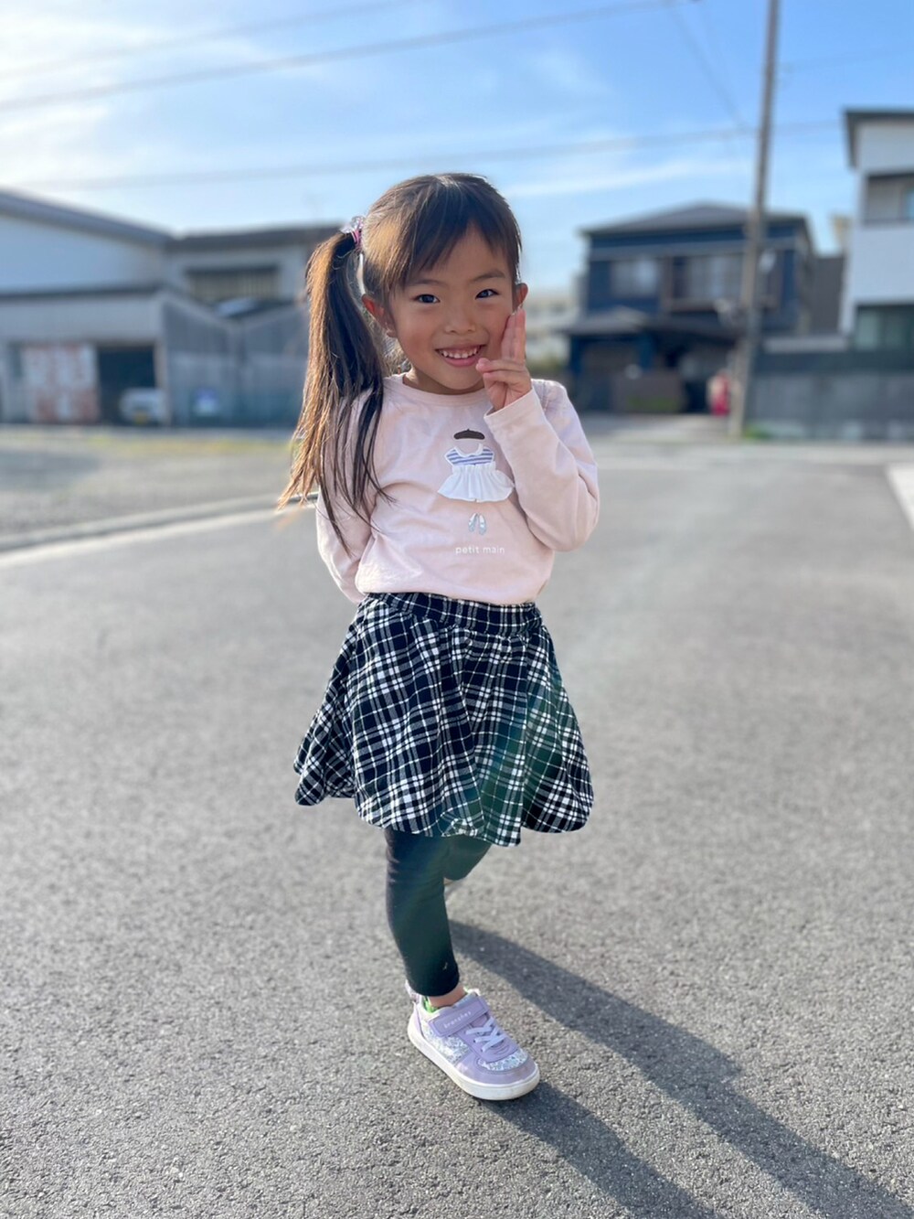 ピンク系のTシャツ/カットソー、ブラック系のスカート、パープル系のスニーカーを着用したキッズの春コーディネートの2枚目の写真