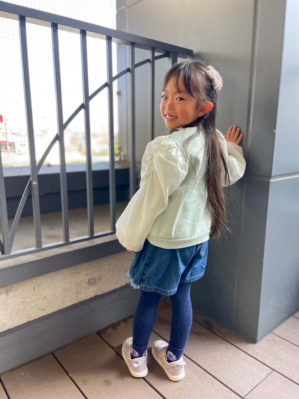 グリーン系のスウェット、ブルー系のデニムパンツ、パープル系のスニーカーを着用したキッズの冬コーディネートの2枚目の写真