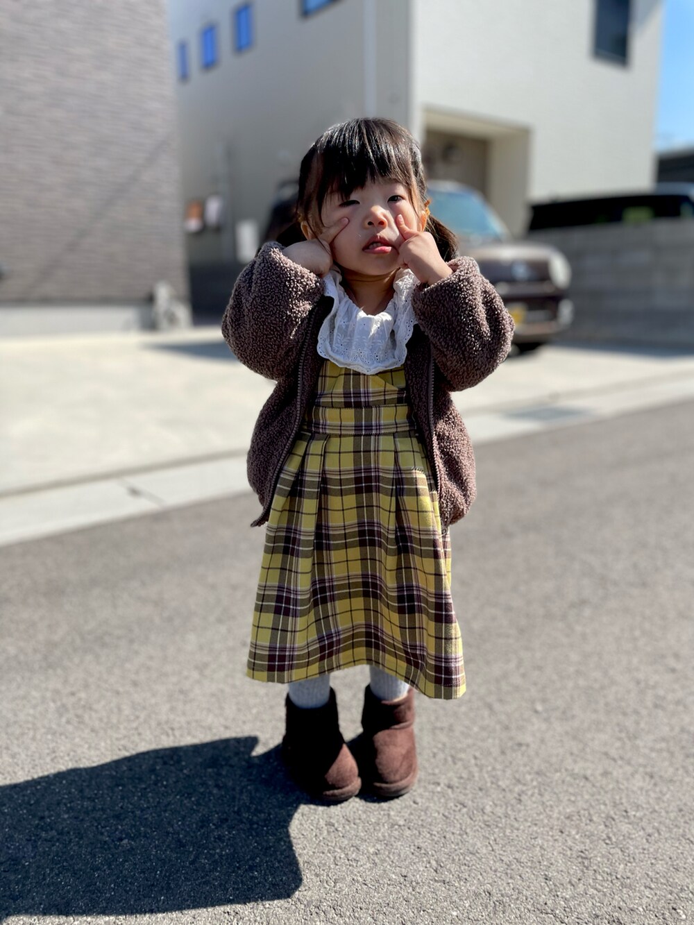 イエロー系のジャンパースカート、ブラウン系のTシャツ/カットソー、ブラウン系のブーツを着用したキッズの春コーディネートの3枚目の写真