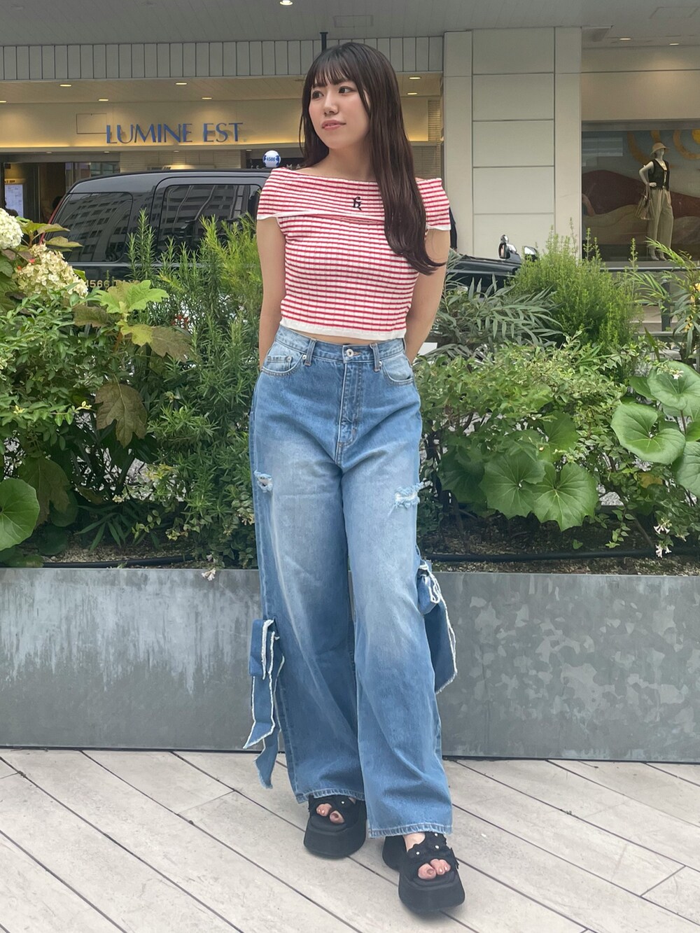 ブルー系のデニムパンツ、ブラック系のサンダル、レッド系のニット/セーターを着用したレディースの夏コーディネートの2枚目の写真