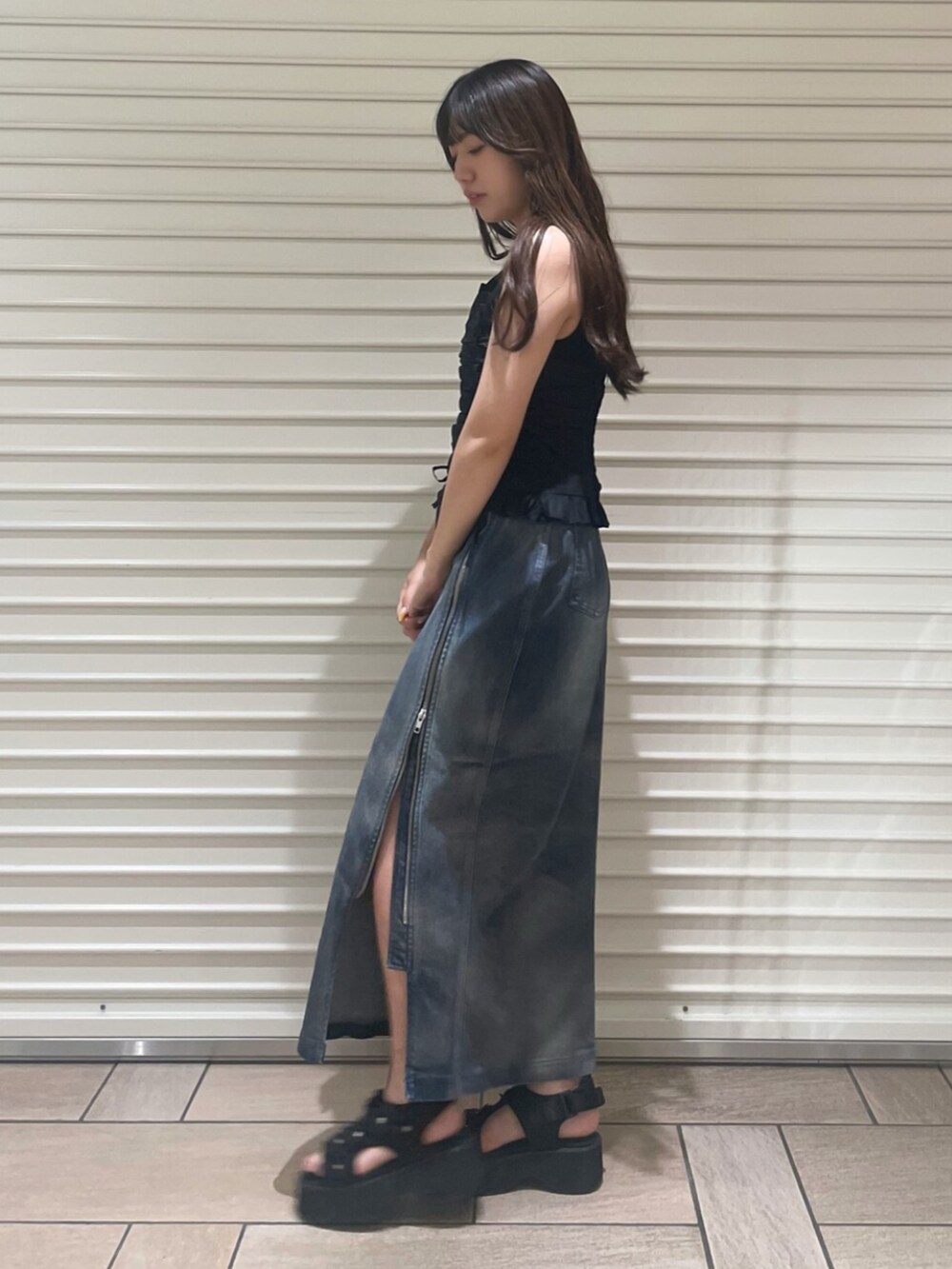 ブラック系のサンダル、ブルー系のスカート、ブラック系のTシャツ/カットソーを着用したレディースの夏コーディネートの2枚目の写真