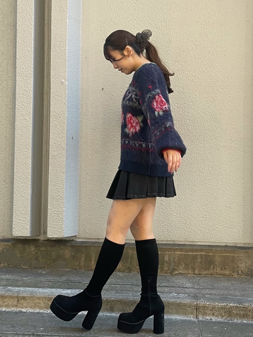 ブルー系のニット/セーター、ブラック系のスカート、ブラック系のブーツを着用したレディースの秋コーディネートの2枚目の写真