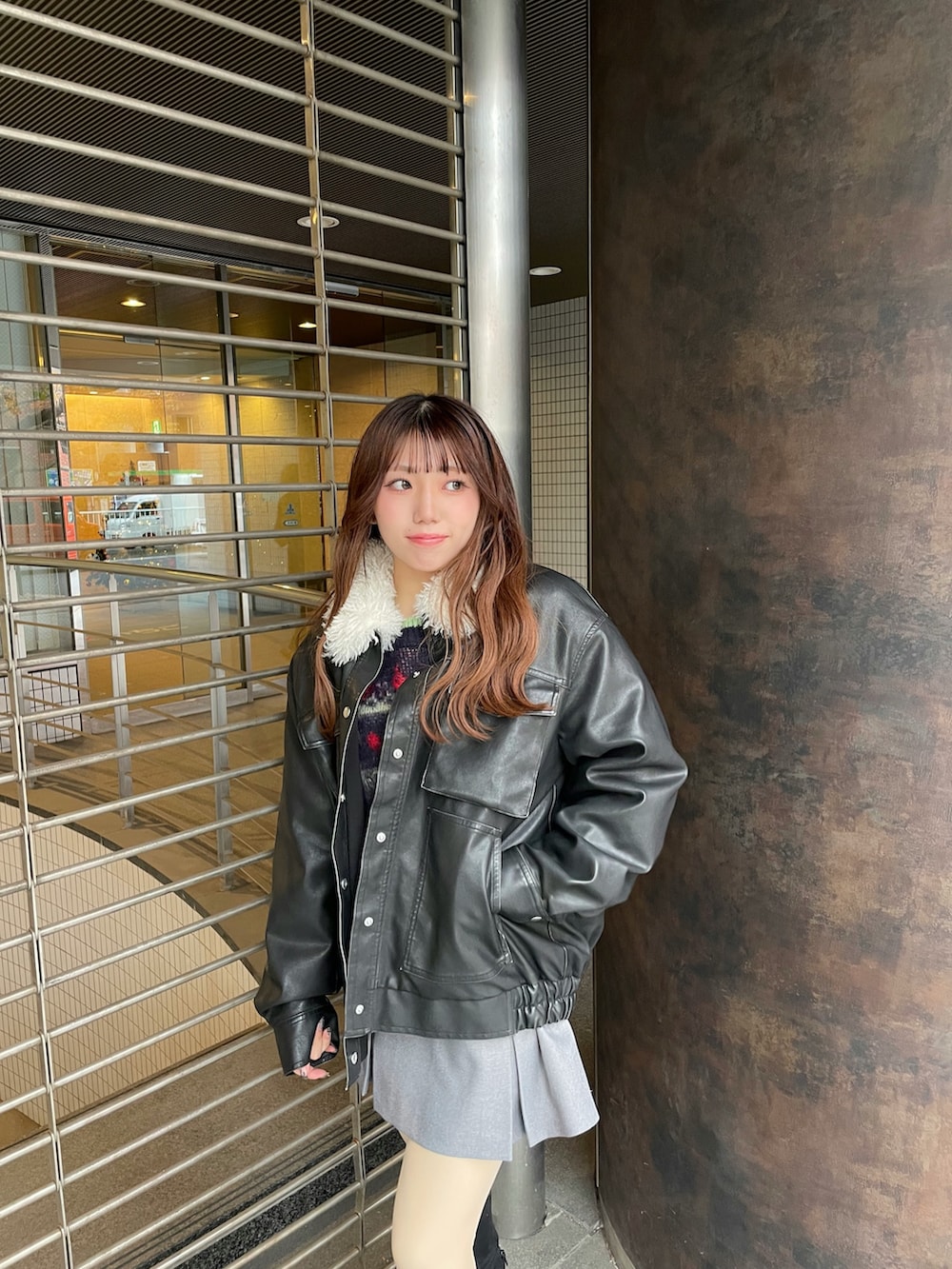 ブラック系のブルゾン、ブルー系のニット/セーター、グレー系のスカートを着用したレディースの秋コーディネートの4枚目の写真