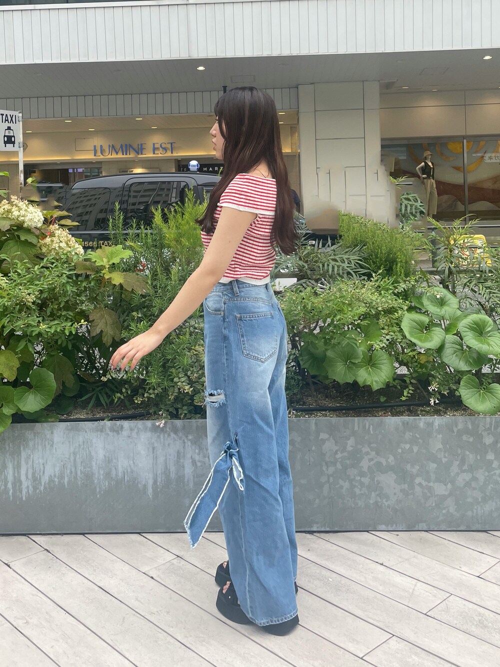 ブルー系のデニムパンツ、ブラック系のサンダル、レッド系のニット/セーターを着用したレディースの夏コーディネートの3枚目の写真