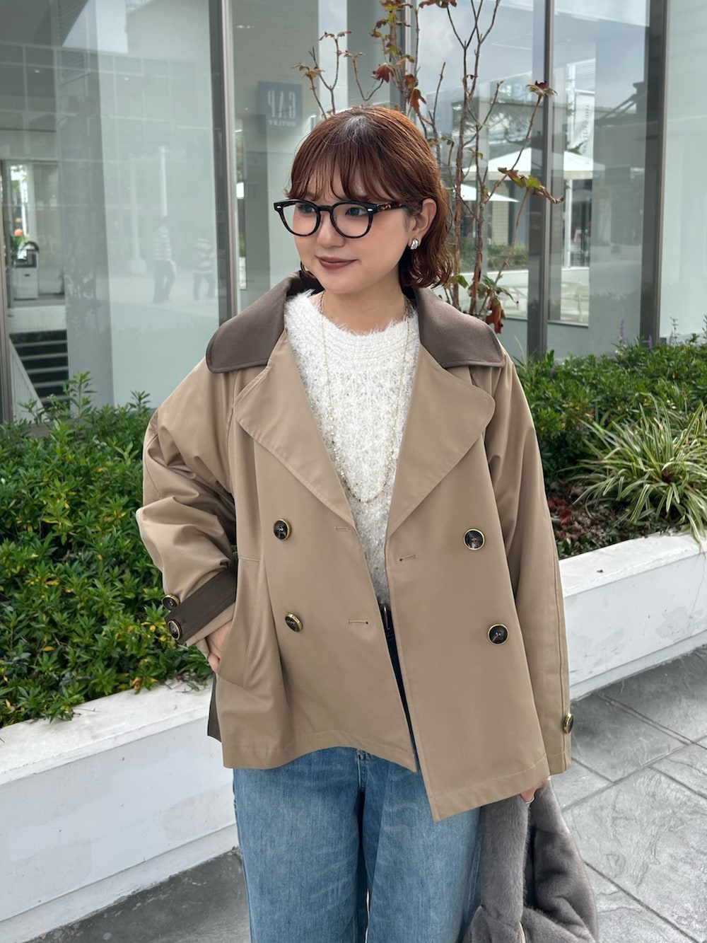 イエロー系のトレンチコート、ホワイト系のニット/セーターを着用したレディースの秋コーディネートの4枚目の写真