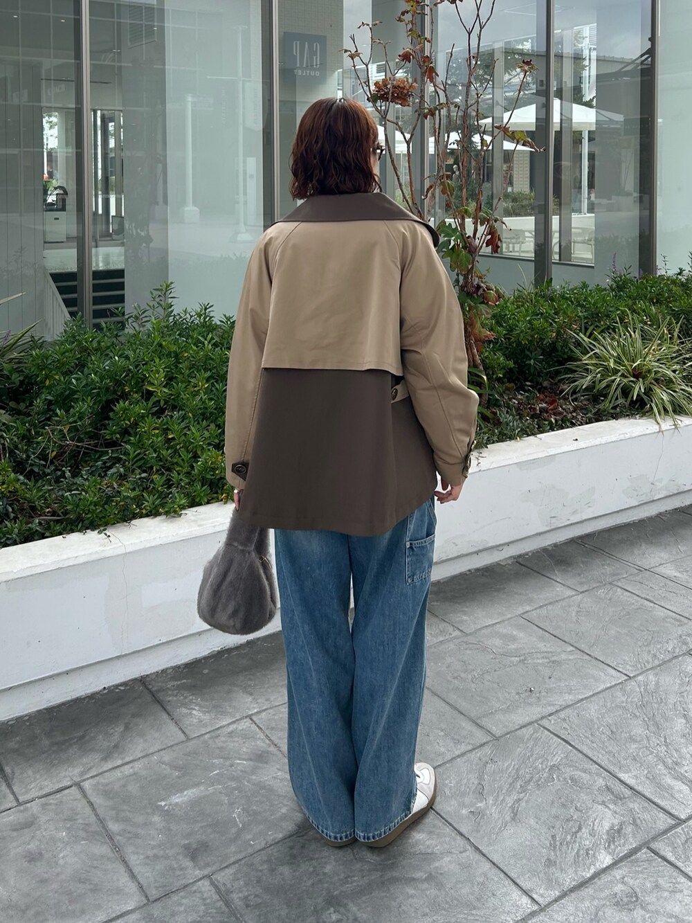 イエロー系のトレンチコート、ホワイト系のニット/セーターを着用したレディースの秋コーディネートの3枚目の写真