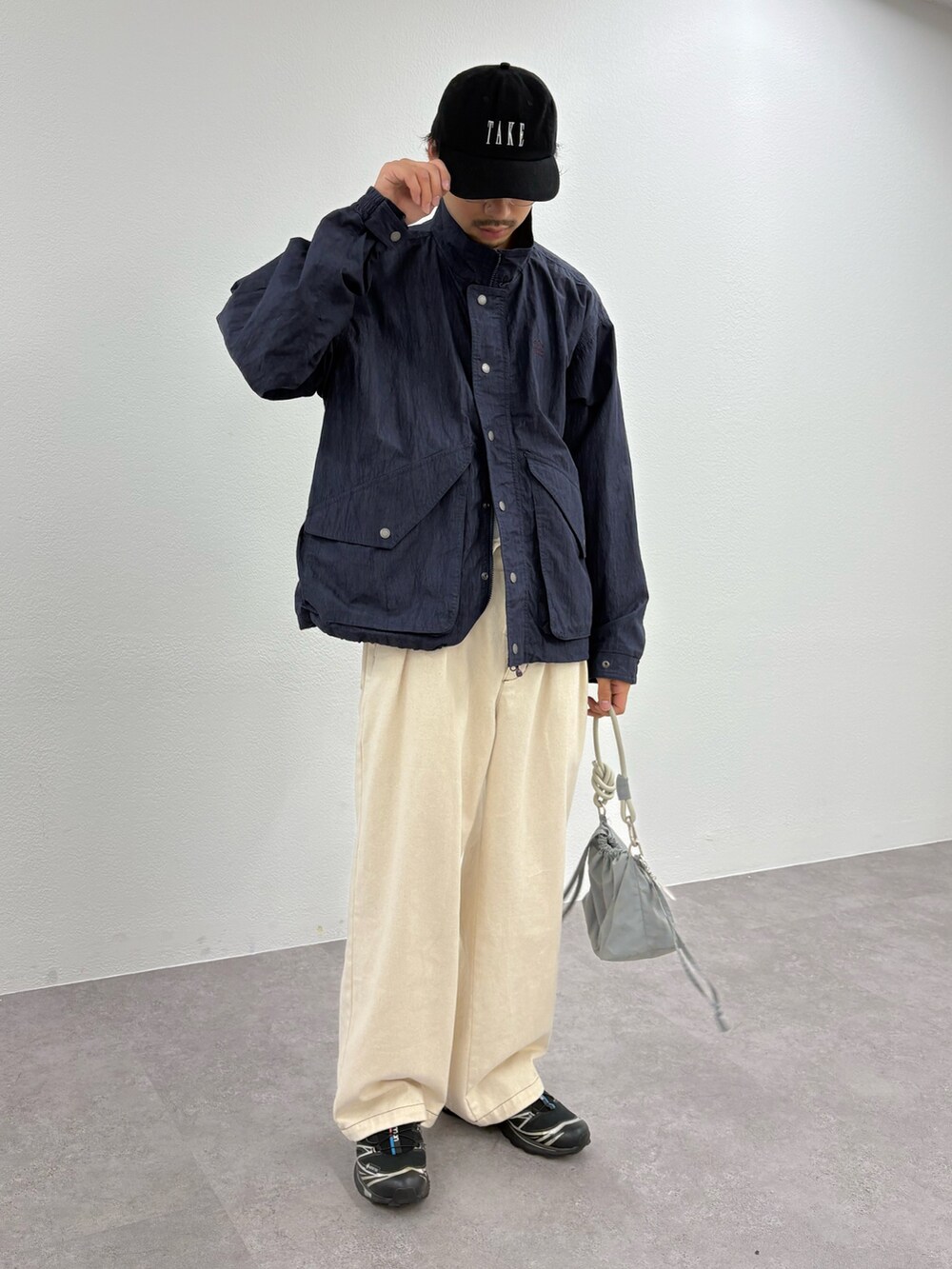 ブルー系のナイロンジャケット、ホワイト系のデニムパンツ、グレー系のショルダーバッグを着用したメンズの秋コーディネートの2枚目の写真