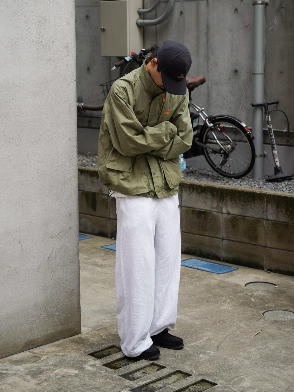 グレー系のスウェットパンツ、グリーン系のナイロンジャケットを着用したメンズの秋コーディネートの2枚目の写真