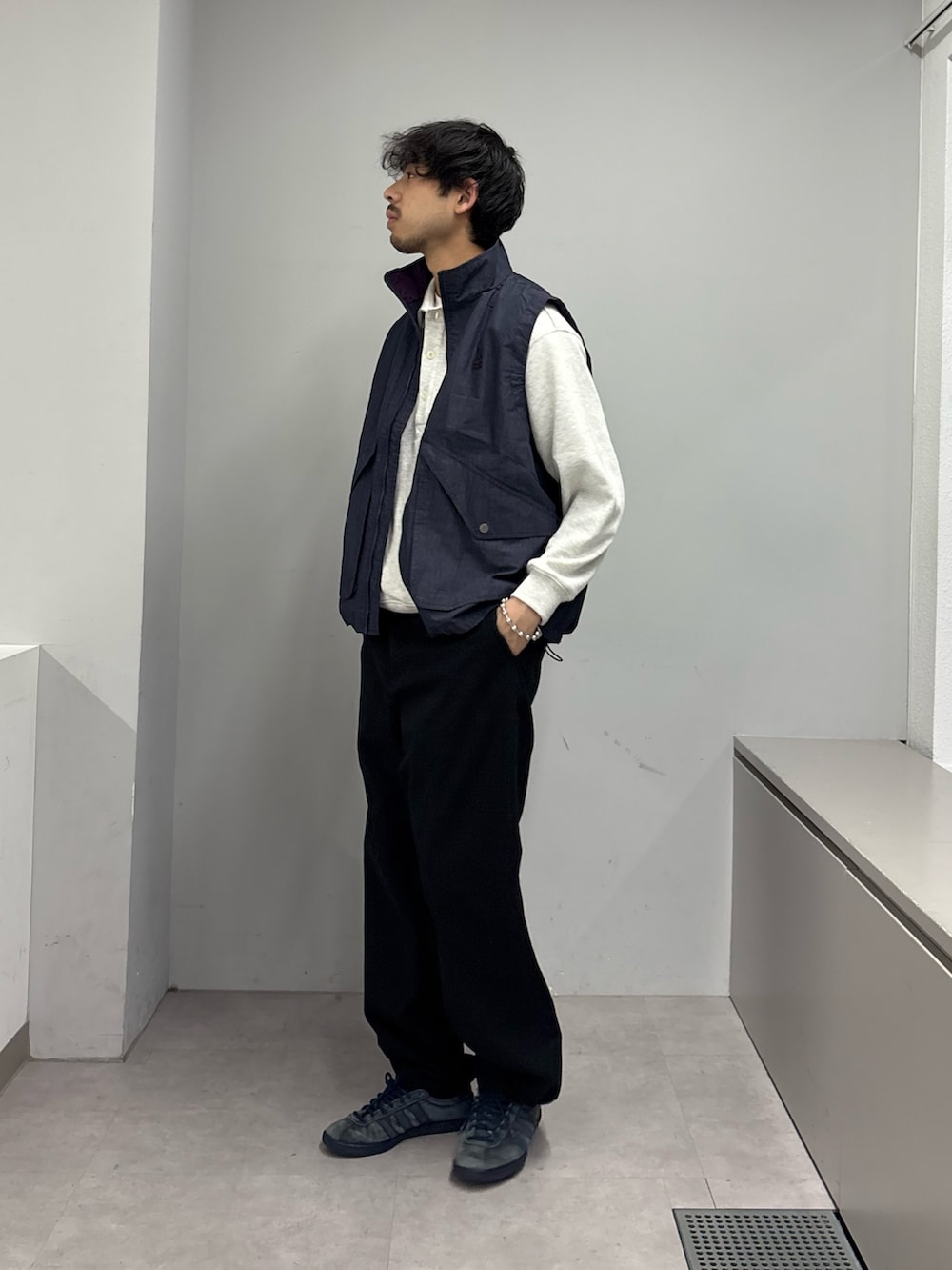 グレー系のチノパンツ、ブルー系のベスト、グレー系のスウェットを着用したメンズの春コーディネートの2枚目の写真