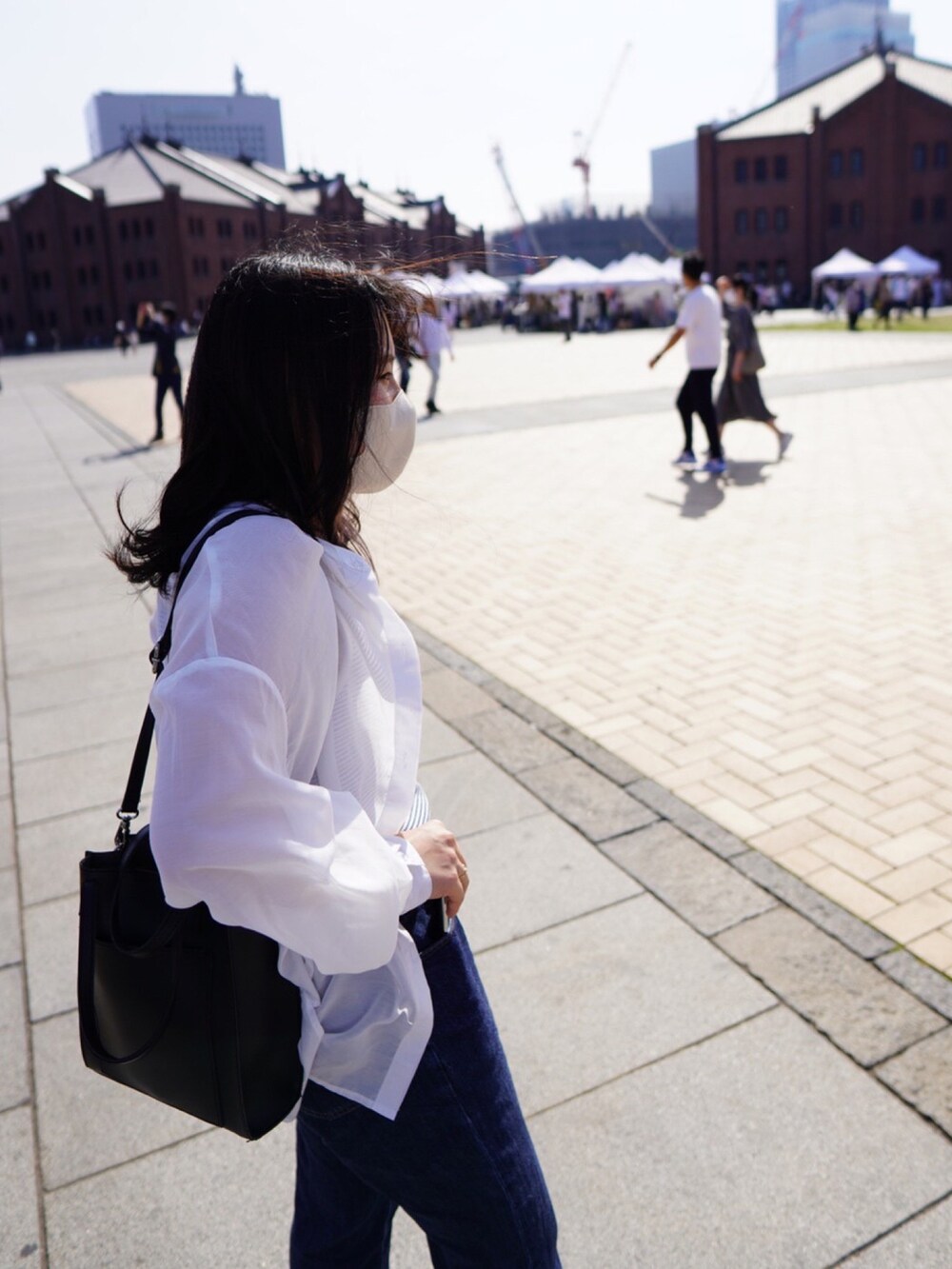 ブラック系のショルダーバッグ、ブルー系のデニムパンツ、ホワイト系のシャツ/ブラウスを着用したレディースの春コーディネートの3枚目の写真