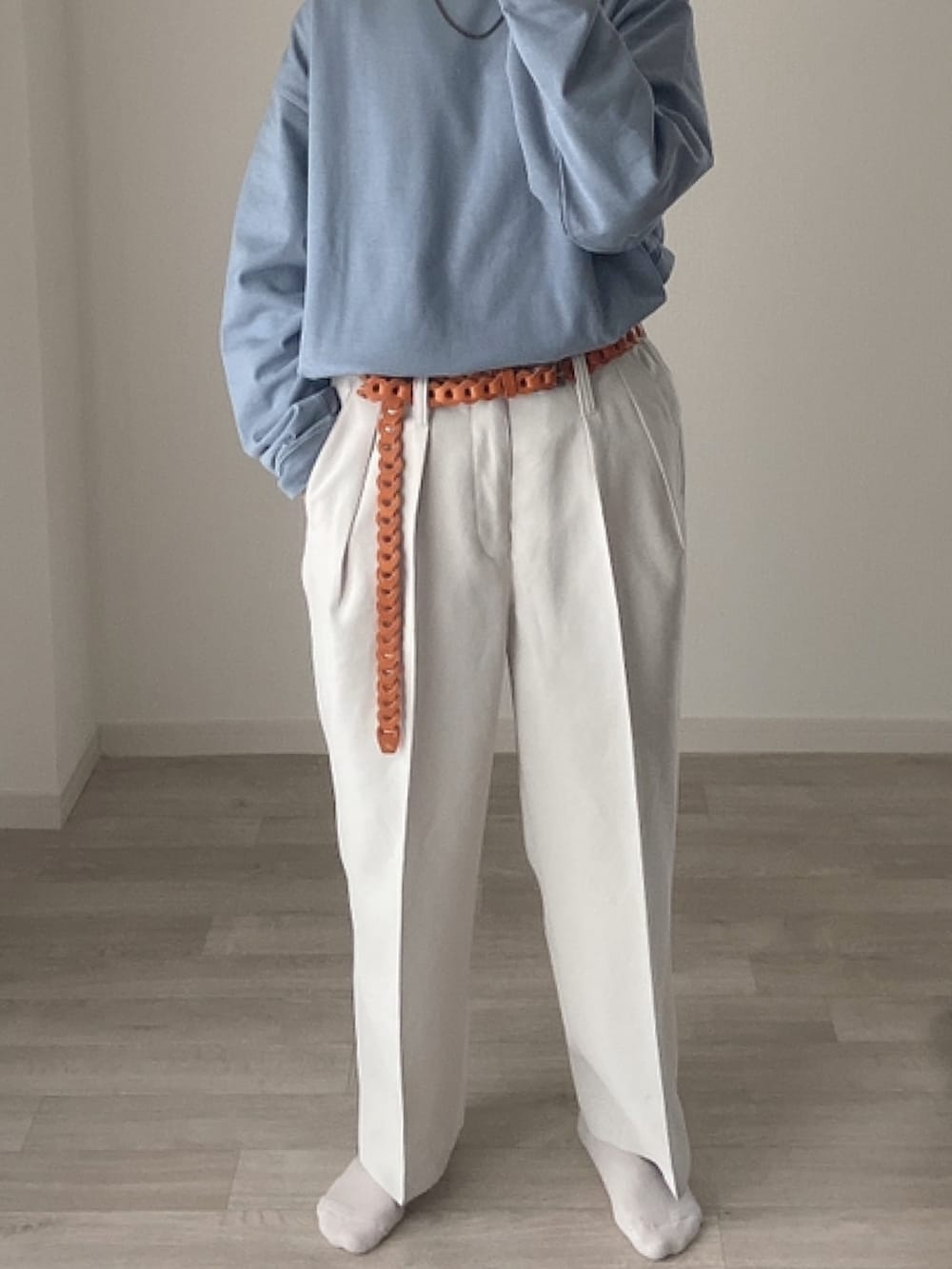 ブラウン系のステンカラーコート、ブルー系のTシャツ/カットソー、ホワイト系のスラックスを着用したレディースの冬コーディネートの4枚目の写真