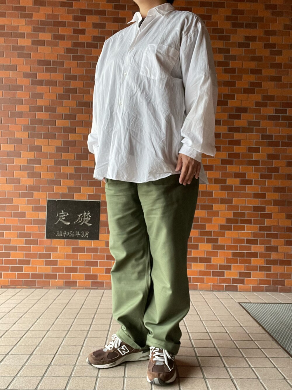 グリーン系のパンツ、ブラウン系のスニーカー、ホワイト系のシャツ/ブラウスを着用したレディースの秋コーディネートの2枚目の写真