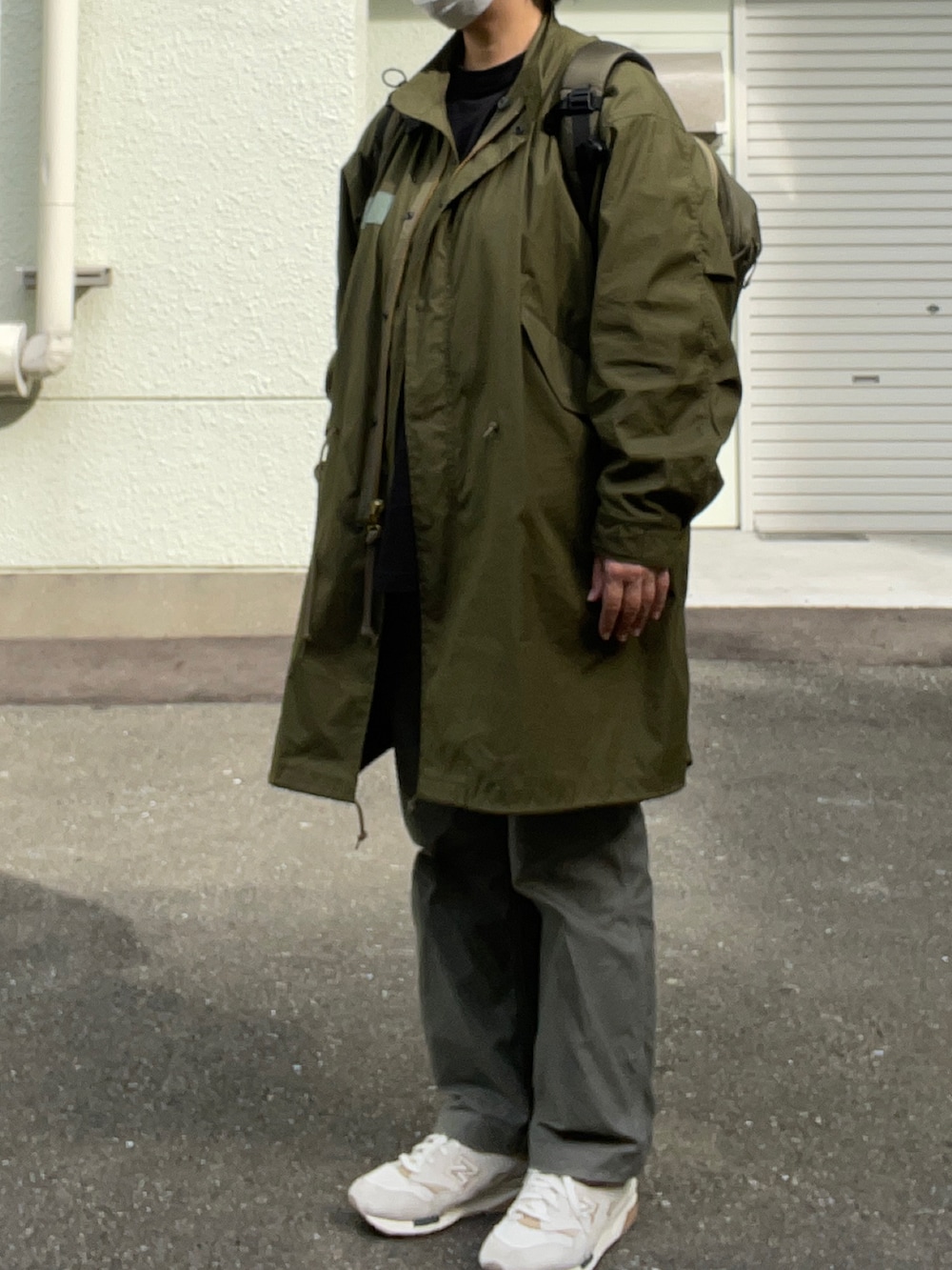 グリーン系のモッズコート、グリーン系のバックパック/リュック、ブラック系のTシャツ/カットソーを着用したレディースの秋コーディネートの2枚目の写真