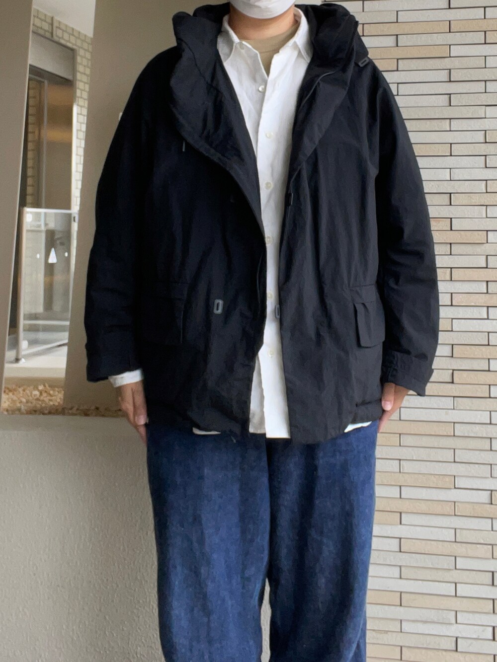 ブラック系のマウンテンパーカー、ブルー系のデニムパンツ、ベージュ系のスニーカーを着用したレディースの秋コーディネートの2枚目の写真