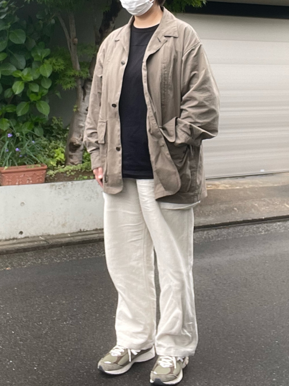 ホワイト系のカーゴパンツ、ベージュ系のカバーオール、グリーン系のスニーカーを着用したレディースの春コーディネートの2枚目の写真