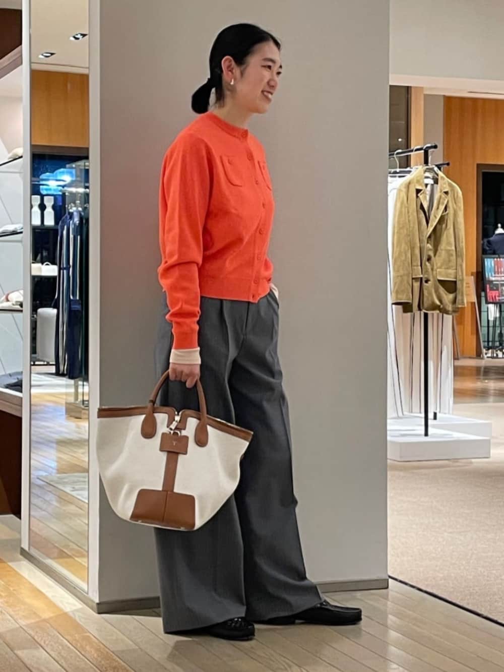 ホワイト系のスラックス、オレンジ系のカーディガン/ボレロを着用したレディースの春コーディネートの2枚目の写真