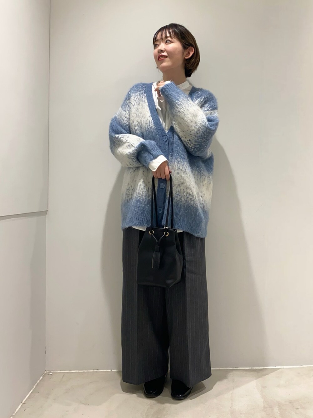ホワイト系のシャツ/ブラウス、ブラック系のショルダーバッグ、ブルー系のカーディガン/ボレロを着用したレディースの秋コーディネートの2枚目の写真