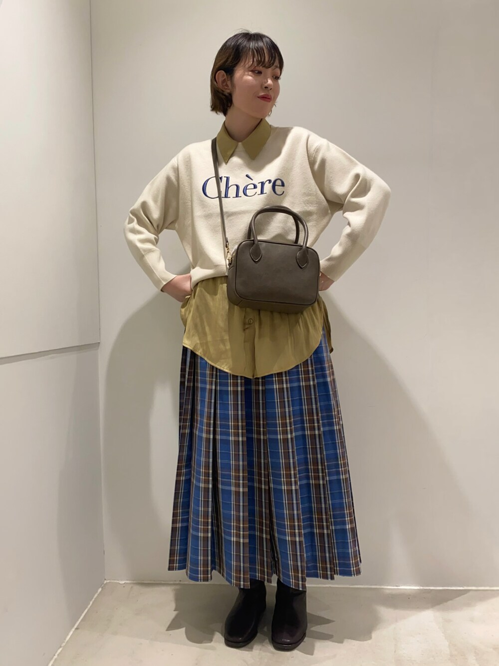 ホワイト系のニット/セーター、ブラウン系のボストンバッグ、イエロー系のシャツ/ブラウスを着用したレディースの秋コーディネートの3枚目の写真