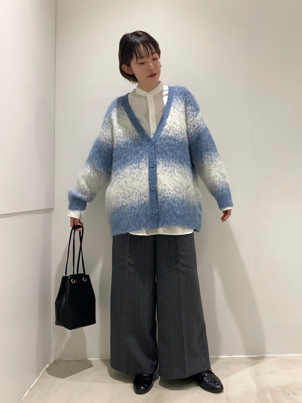 ホワイト系のシャツ/ブラウス、ブラック系のショルダーバッグ、ブルー系のカーディガン/ボレロを着用したレディースの秋コーディネートの3枚目の写真