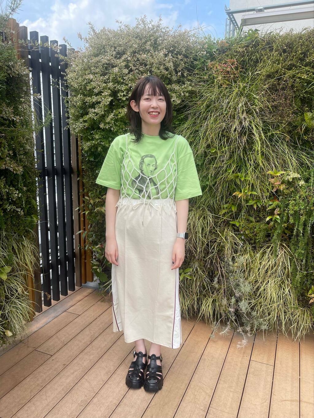 グリーン系のTシャツ/カットソー、ホワイト系のスカート、ホワイト系のその他小物を着用したレディースの夏コーディネートの2枚目の写真