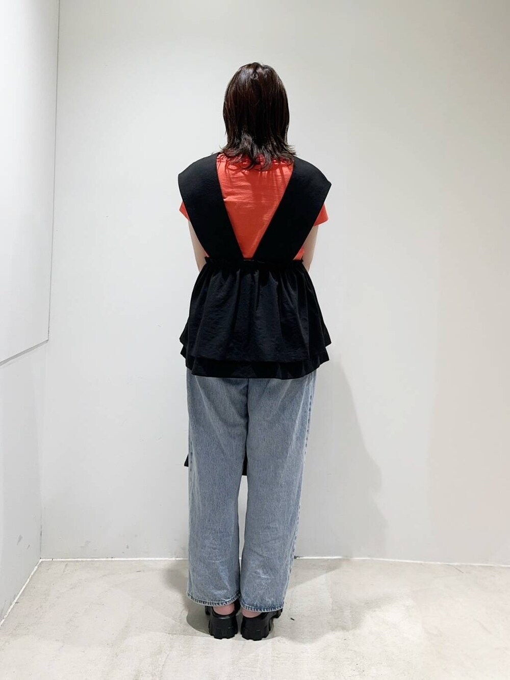 ブルー系のデニムパンツ、ブラック系のトートバッグ、オレンジ系のTシャツ/カットソーを着用したレディースの夏コーディネートの3枚目の写真