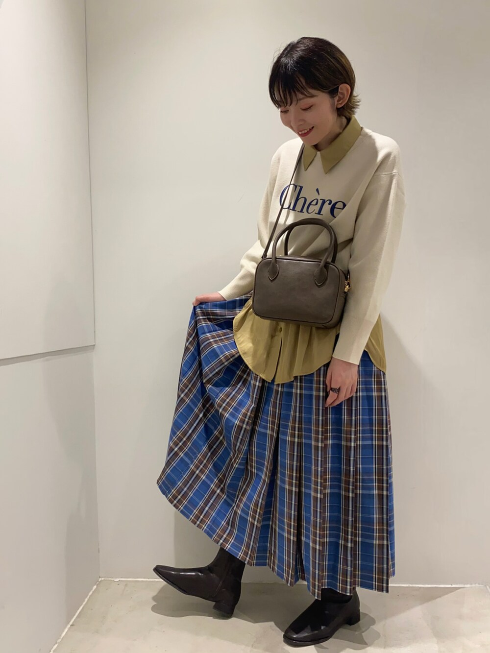 ホワイト系のニット/セーター、ブラウン系のボストンバッグ、イエロー系のシャツ/ブラウスを着用したレディースの秋コーディネートの2枚目の写真