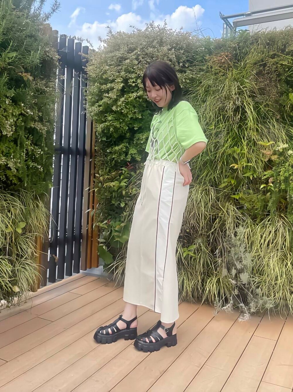 グリーン系のTシャツ/カットソー、ホワイト系のスカート、ホワイト系のその他小物を着用したレディースの夏コーディネートの3枚目の写真