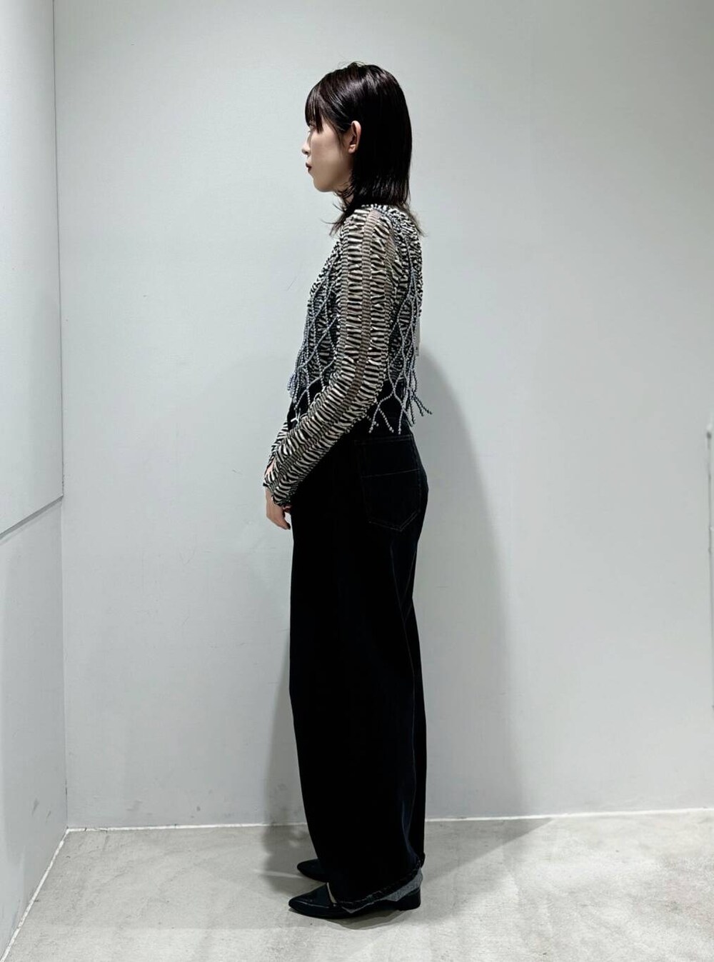 ブラック系のパンプス、ブラック系のデニムパンツ、ブラック系のニット/セーターを着用したレディースの夏コーディネートの2枚目の写真