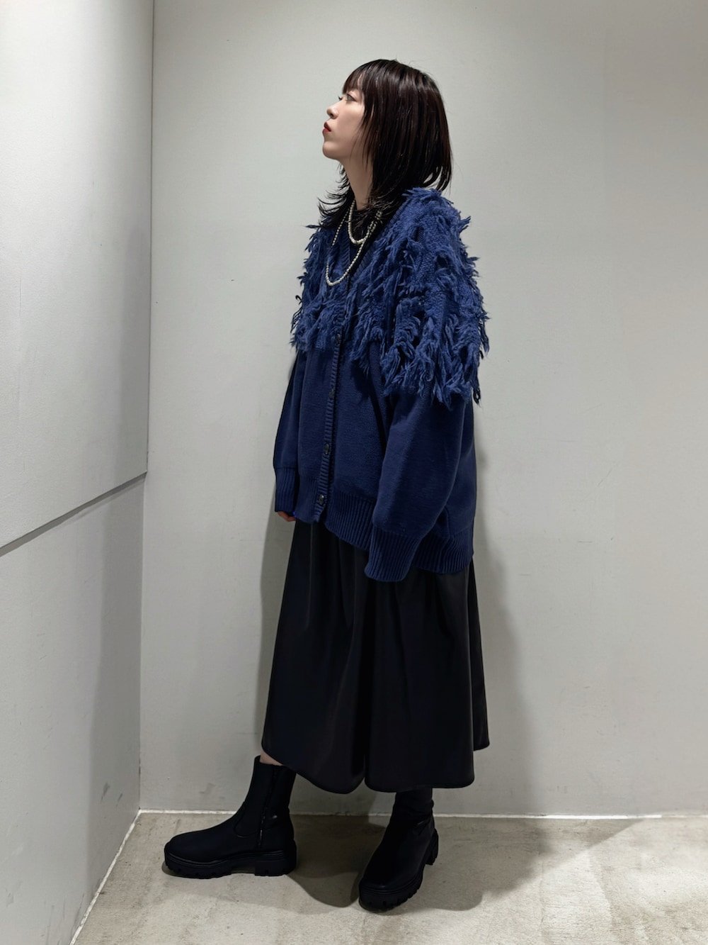 ブルー系のニット/セーター、ブルー系のカーディガン/ボレロ、ブラック系のスカートを着用したレディースの秋コーディネートの2枚目の写真