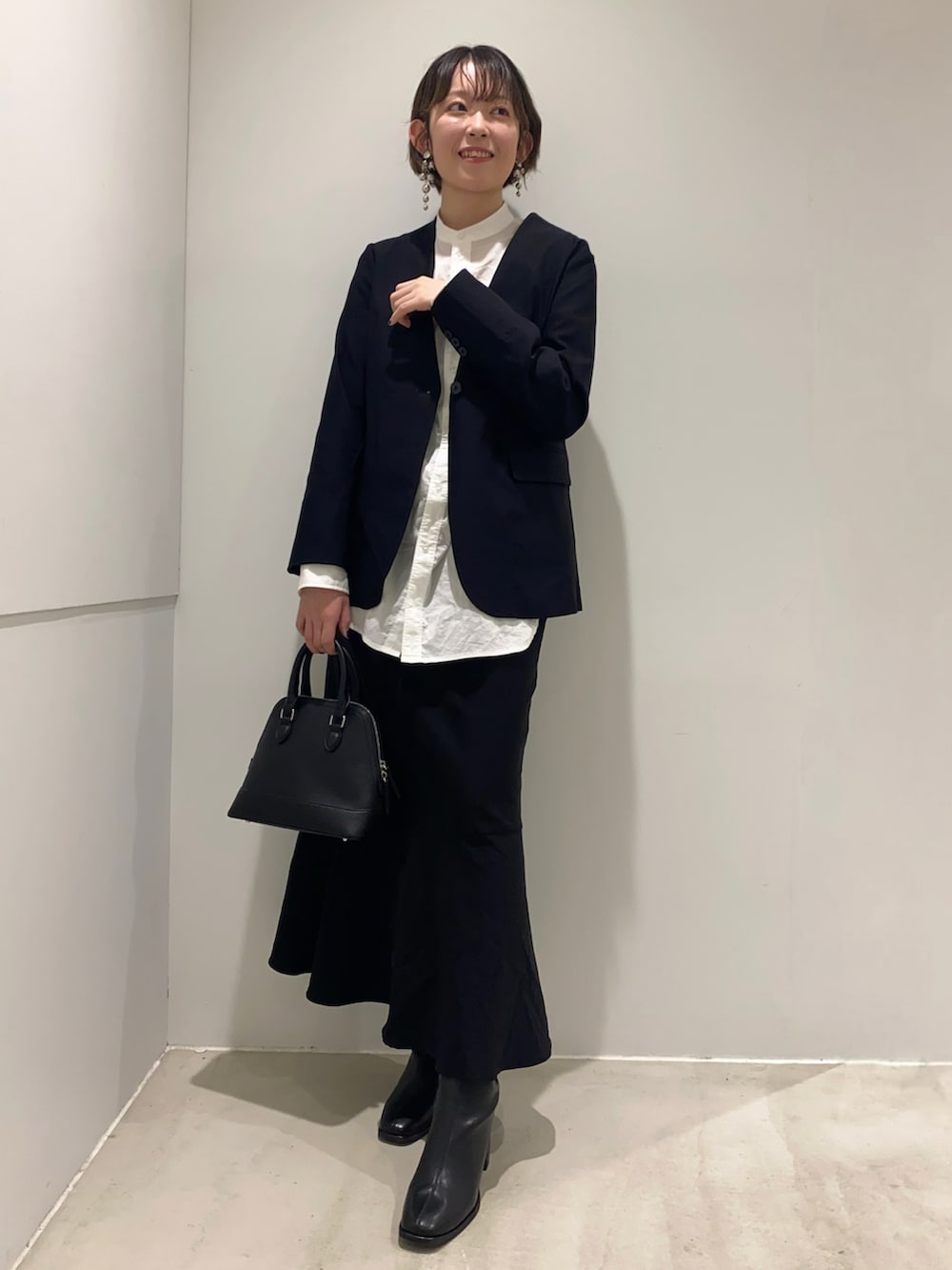 ホワイト系のシャツ/ブラウス、ブラック系のノーカラージャケット、ブラック系のスカートを着用したレディースの秋コーディネートの2枚目の写真