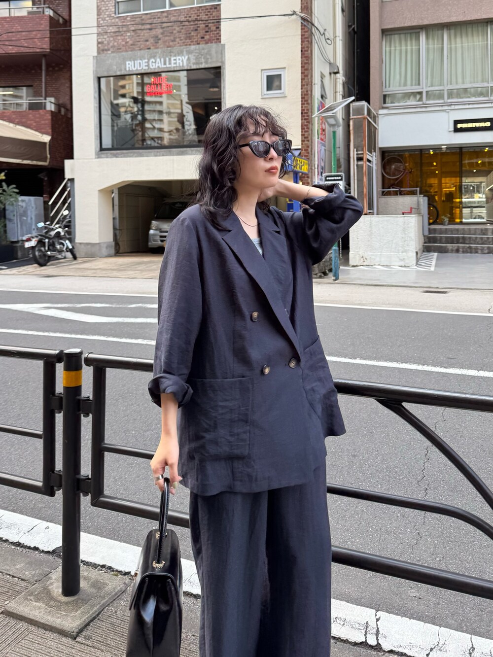 ブルー系のテーラードジャケット、ブルー系のその他パンツ、ブラック系のショルダーバッグを着用したレディースの春コーディネートの4枚目の写真
