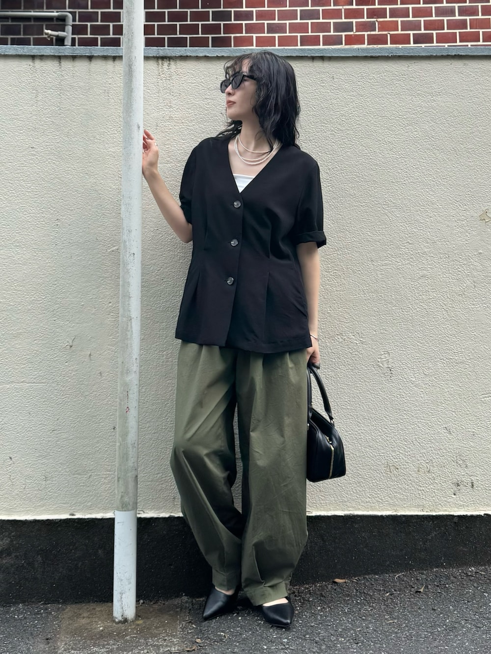 ブラック系のテーラードジャケット、グリーン系のその他パンツ、ブラック系のショルダーバッグを着用したレディースの春コーディネートの2枚目の写真