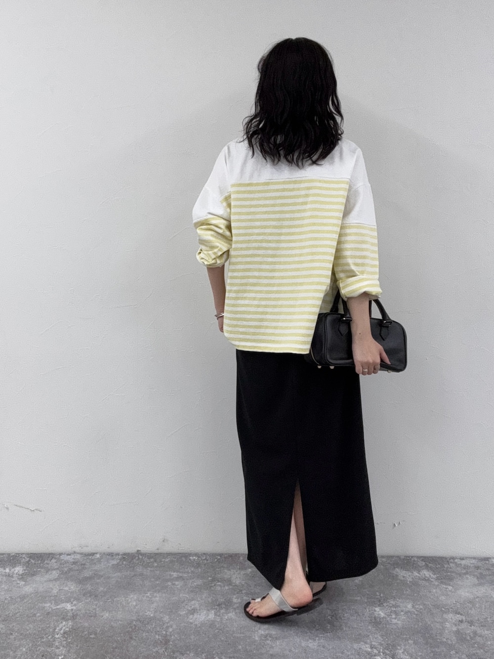 イエロー系のTシャツ/カットソー、ブラック系のスカート、ブラック系のショルダーバッグを着用したレディースの春コーディネートの4枚目の写真