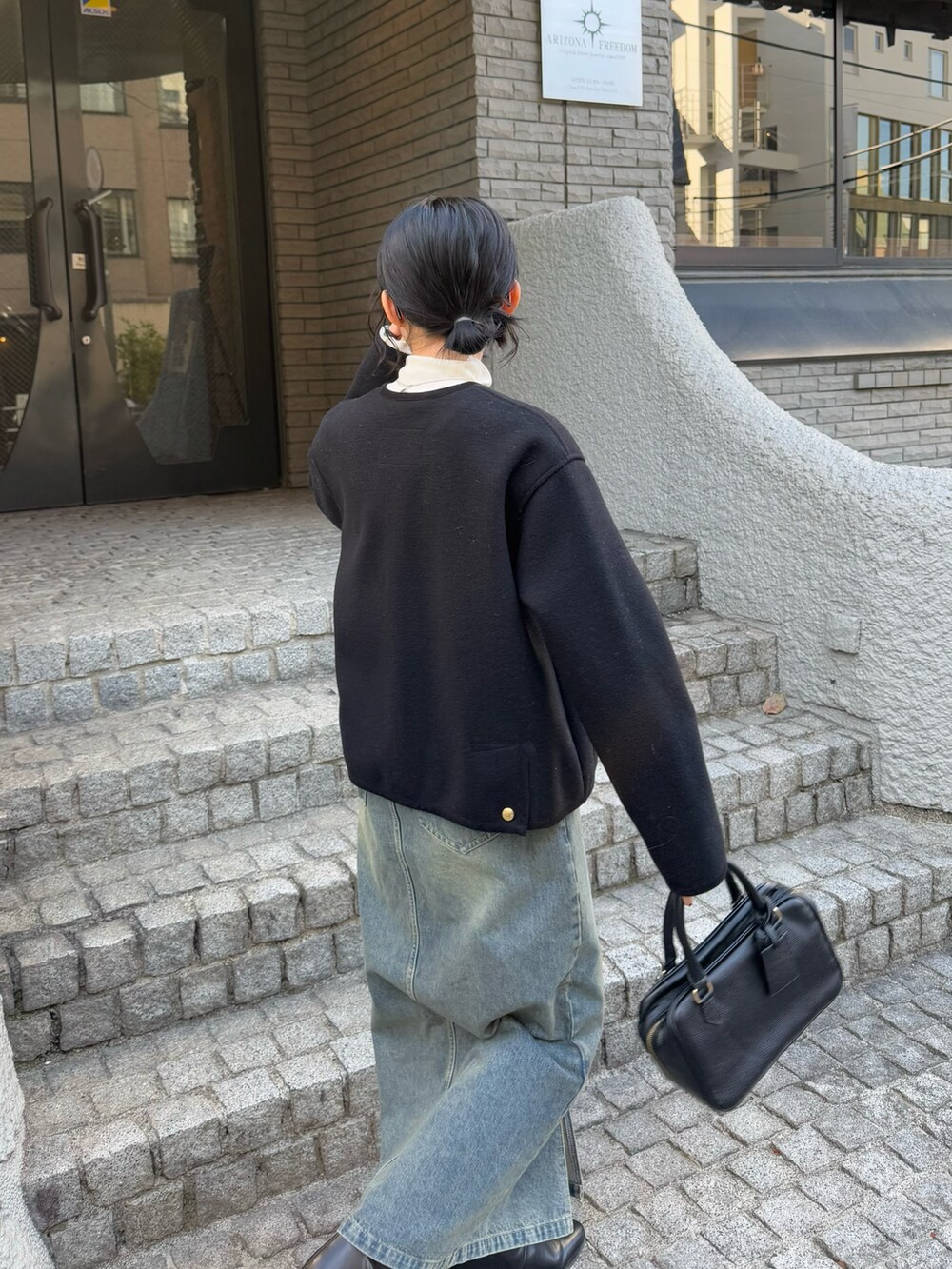 ブラック系のブルゾン、ホワイト系のその他トップス、ブラック系のハンドバッグを着用したレディースの冬コーディネートの5枚目の写真
