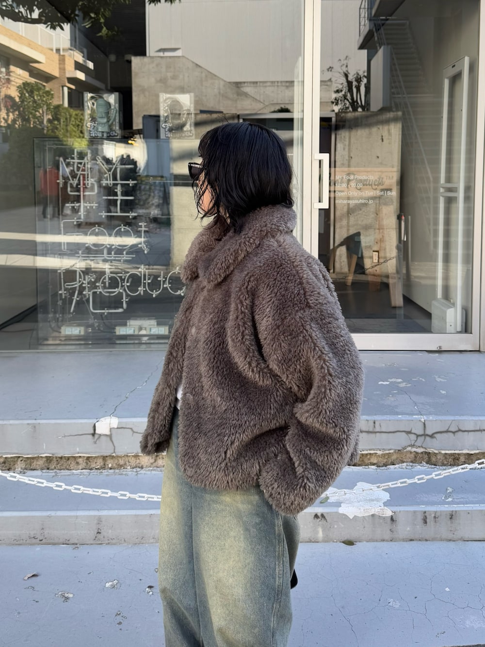 グレー系のムートンコート、グレー系のニット/セーター、ブラック系のハンドバッグを着用したレディースの冬コーディネートの6枚目の写真