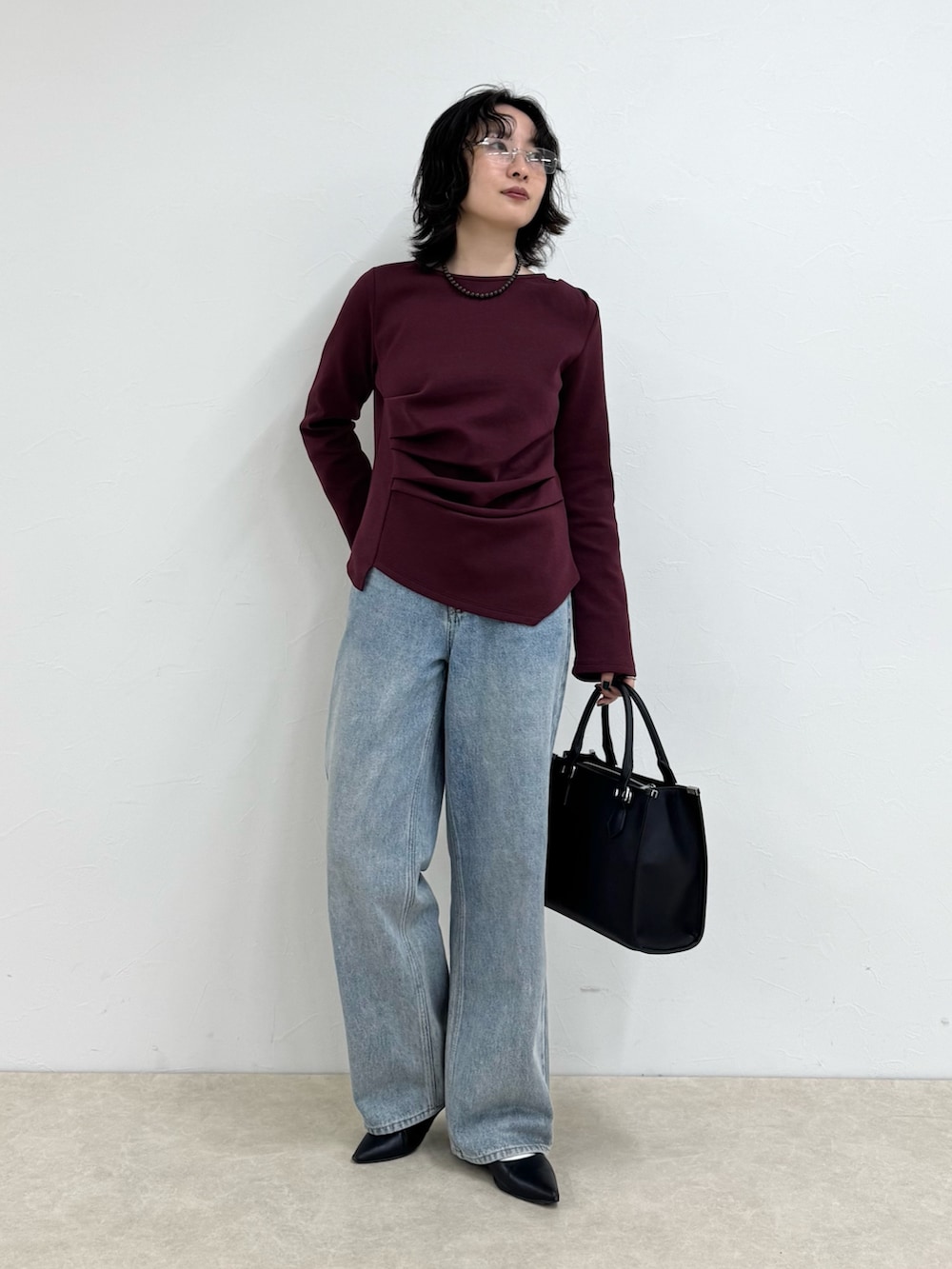 レッド系のTシャツ/カットソー、ブルー系のデニムパンツ、ブラック系のボストンバッグを着用したレディースの秋コーディネートの2枚目の写真