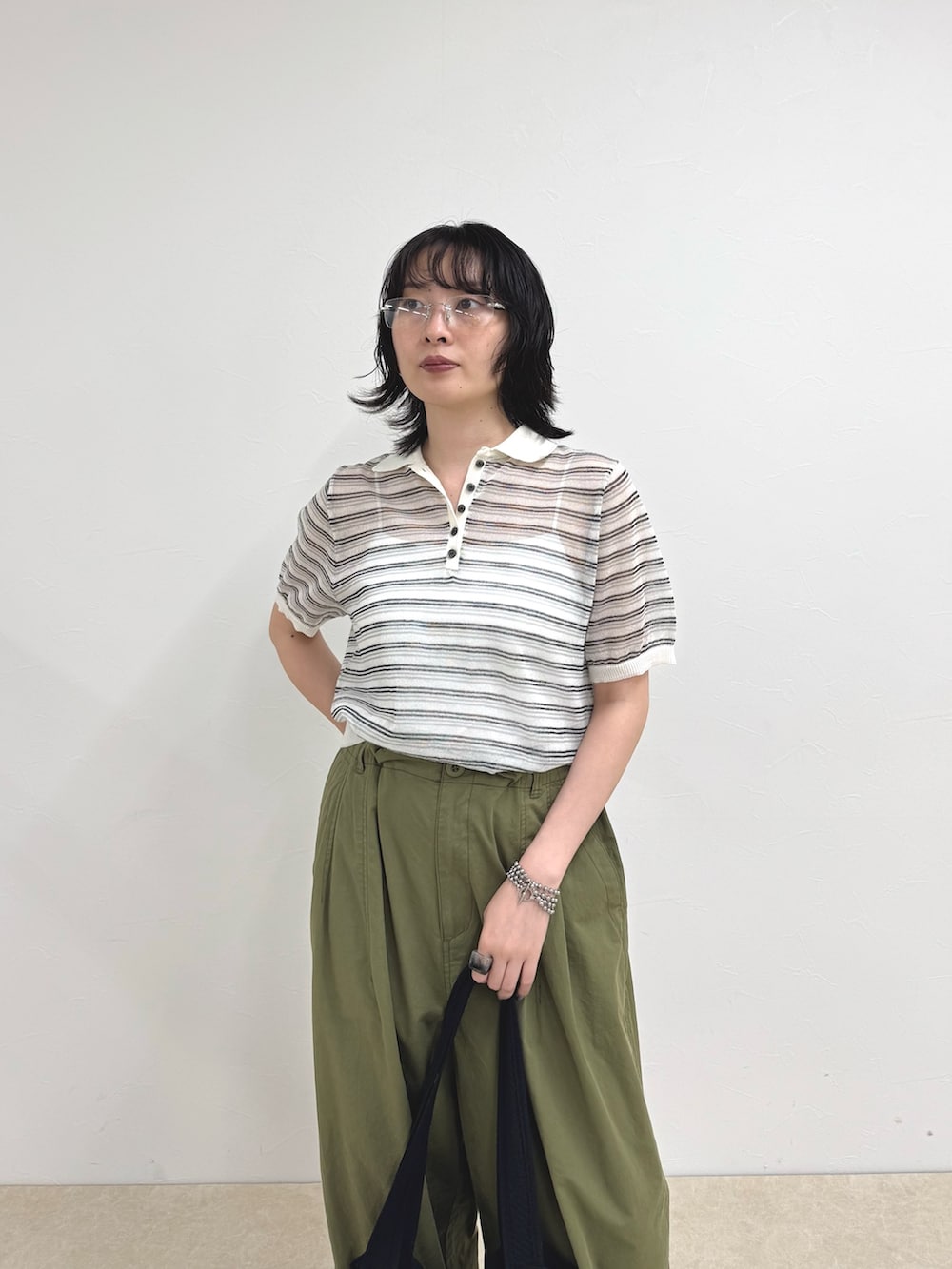 ホワイト系のポロシャツ、グリーン系のその他パンツ、ブラック系のトートバッグを着用したレディースの夏コーディネートの5枚目の写真