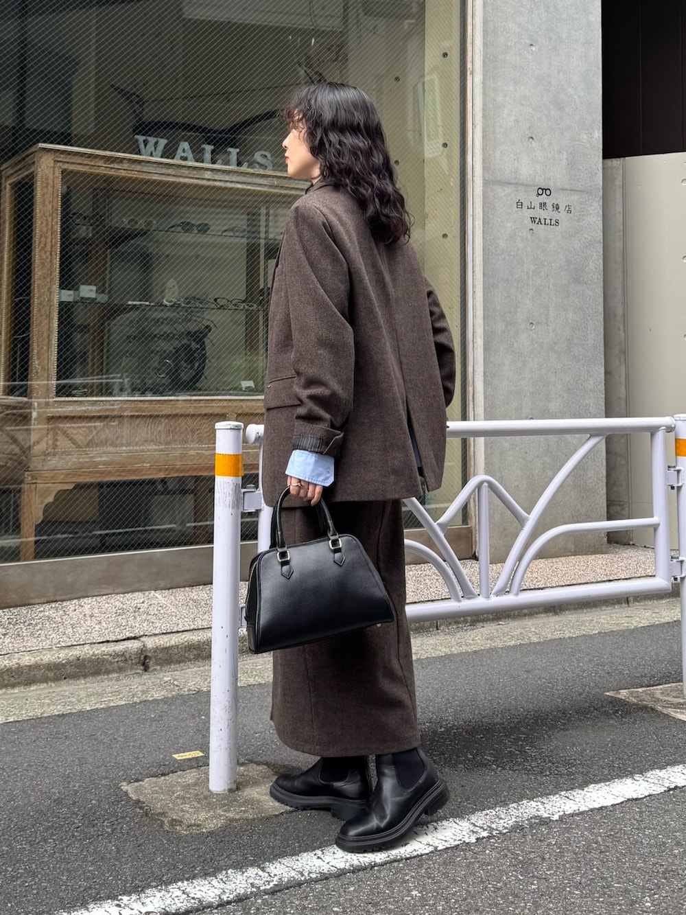 ブラウン系のテーラードジャケット、ブルー系のシャツ/ブラウス、ブラウン系のスカートを着用したレディースの秋コーディネートの4枚目の写真