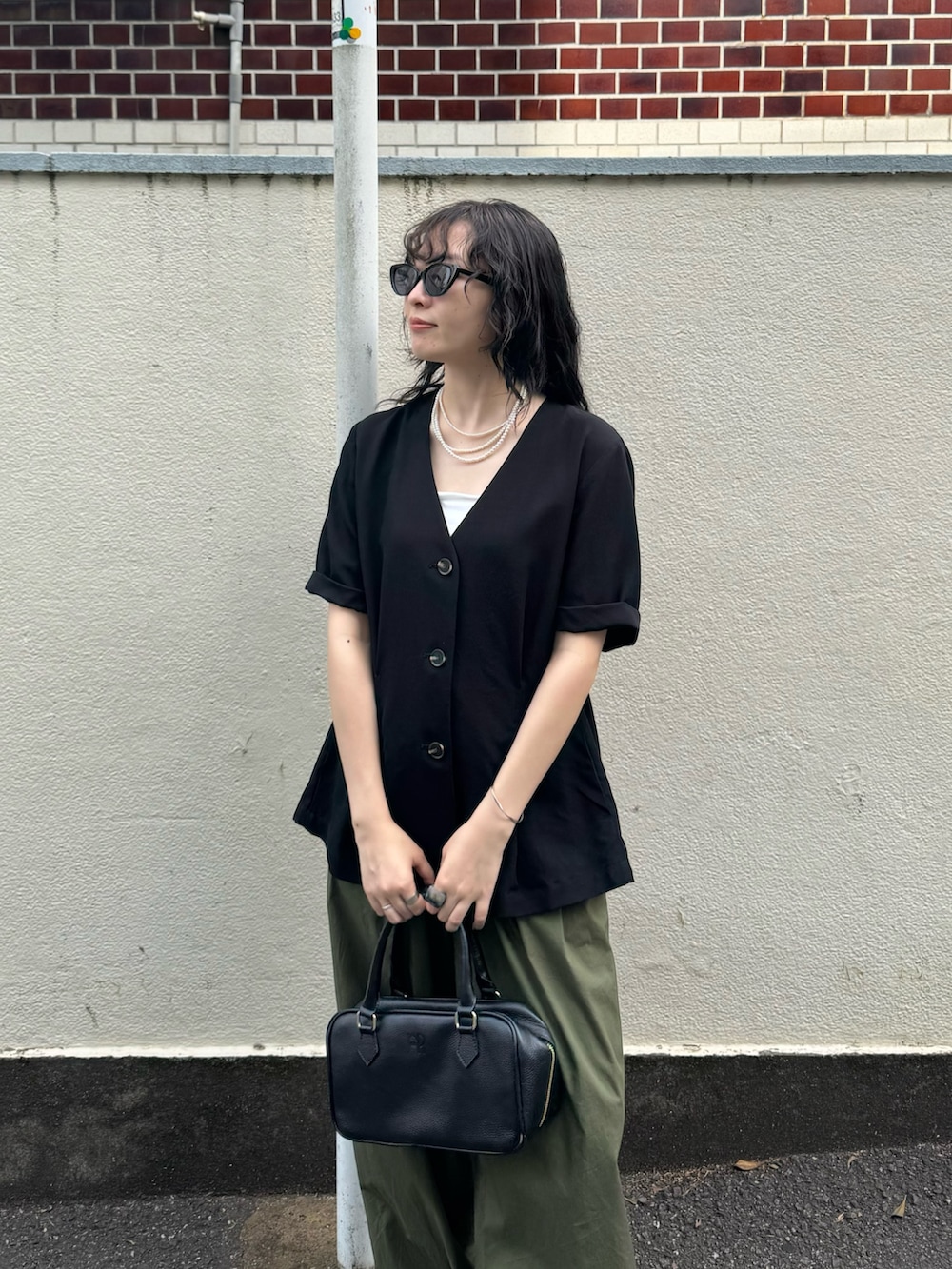 ブラック系のテーラードジャケット、グリーン系のその他パンツ、ブラック系のショルダーバッグを着用したレディースの春コーディネートの5枚目の写真